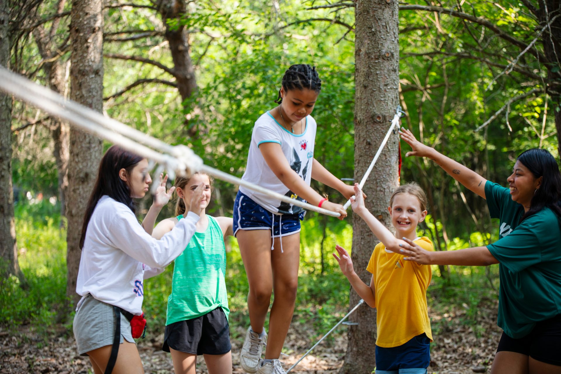 Campers helping each other through a low ropes course