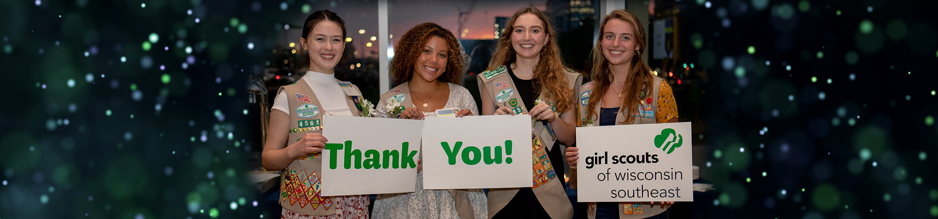  Portrait of four older Girl Scouts holding up Thank You signs at fundraising event 