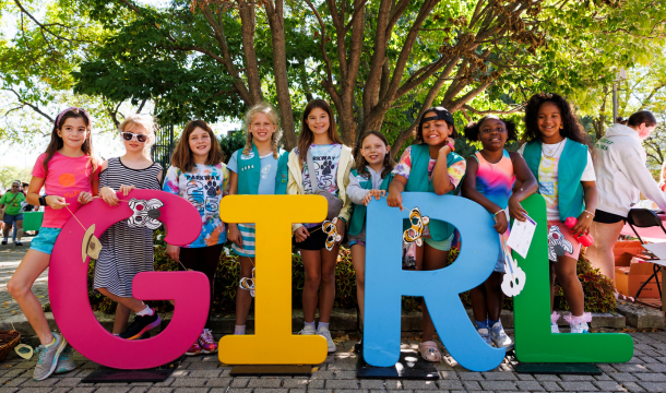 girl scouts standing in front of big letters that spell GIRL