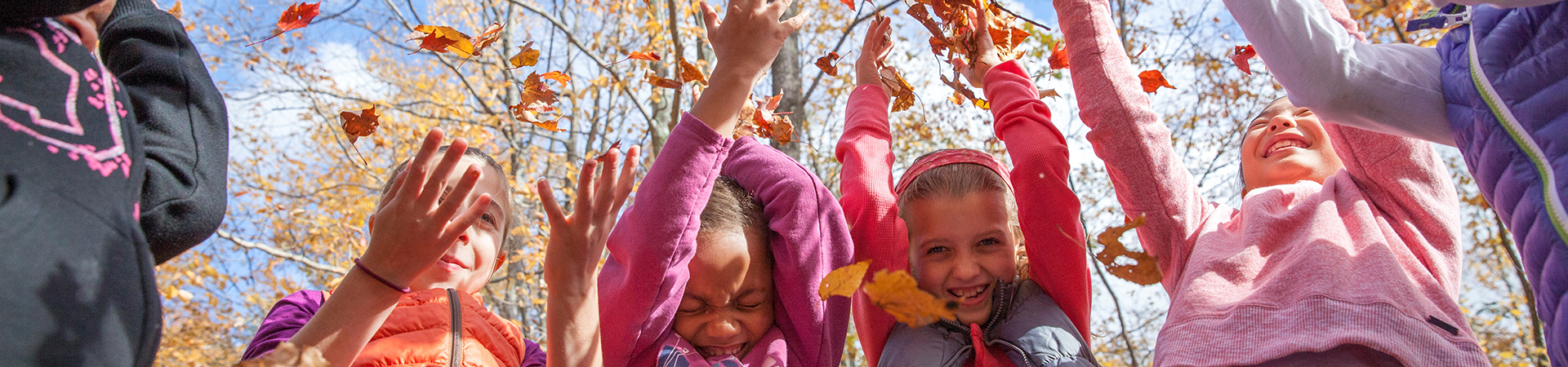  Girl Scouts throwing fall leaves and smiling 