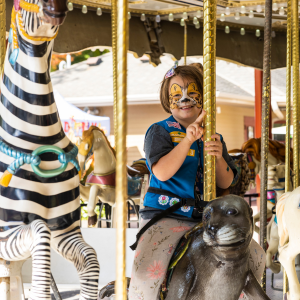 girl scout with tiger face paint on carousel at zoo