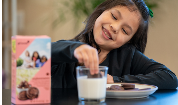 girl scout dunking exploremores into glass of milk