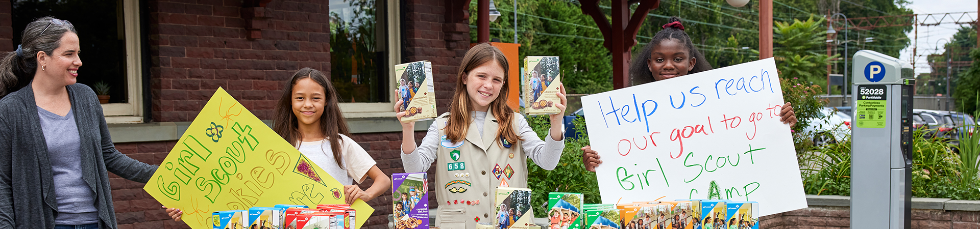  Three Girl Scouts selling cookies at a cookie booth 
