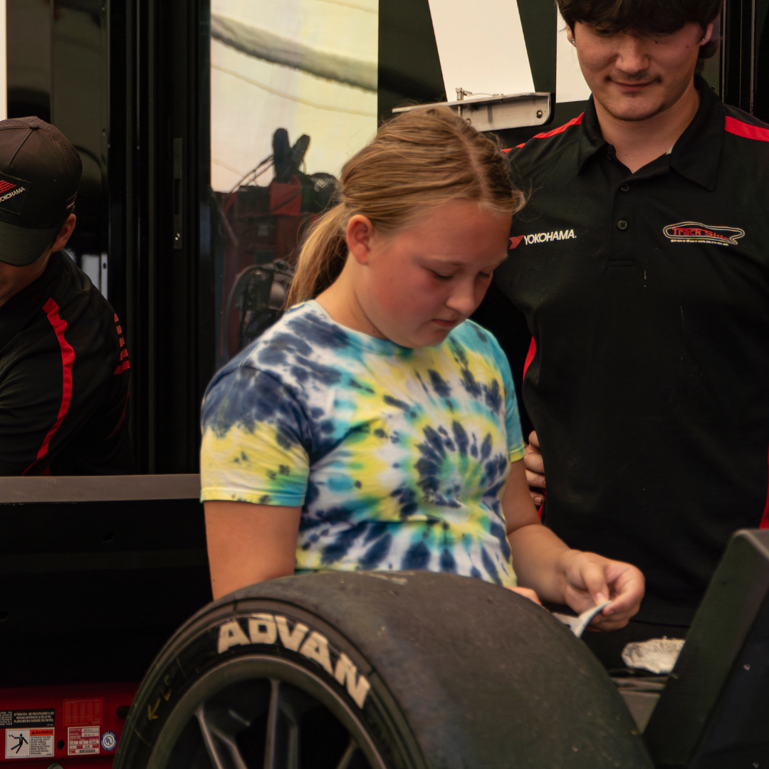 mechanic teaching girl scout about tire and cars