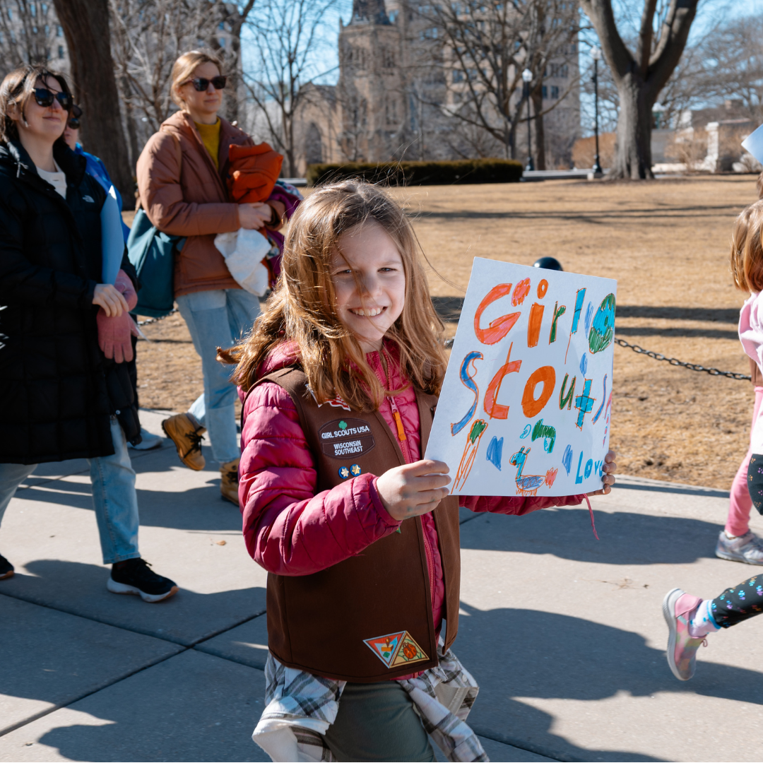 girl scout holding handmade sign walking around the capitol in wisconsin