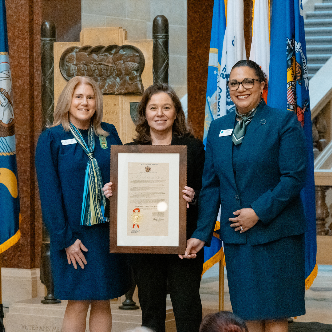 two girl scout executives and lieutenant governor holding proclamation at state capitol