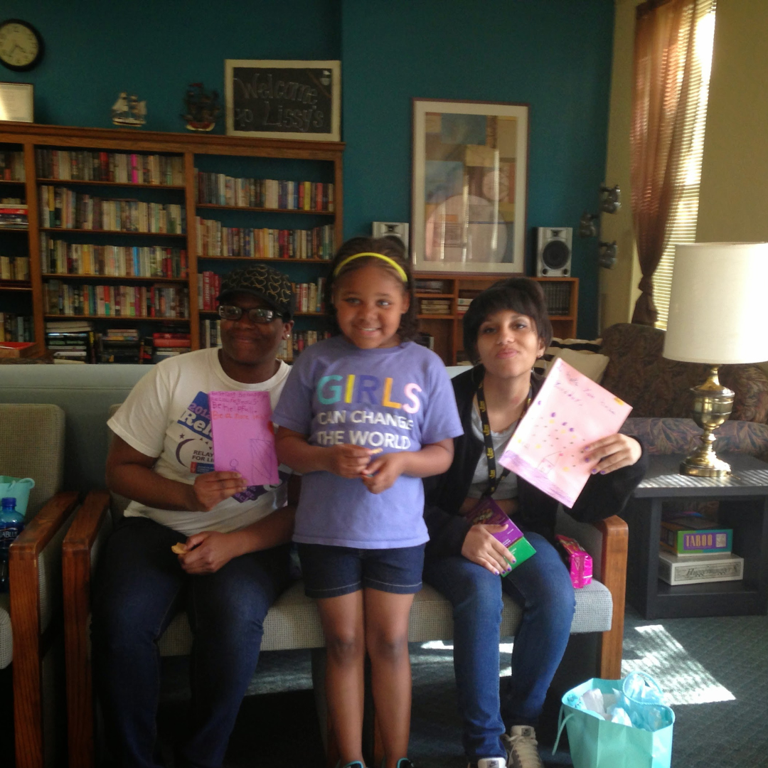 girl scout posing with two others holding cards