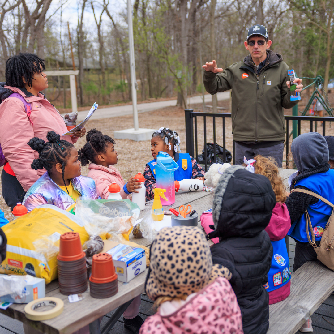 girl scout volunteer directing troop on outdoor stem activity