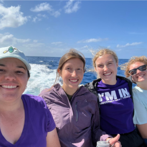 four girl scouts smiling at camera on a boat