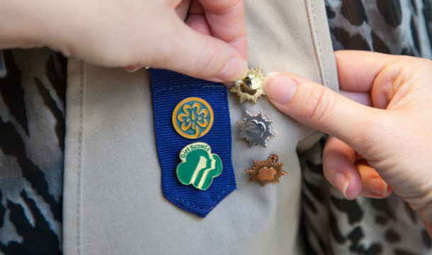 pinning a gold award girl scout on khaki vest