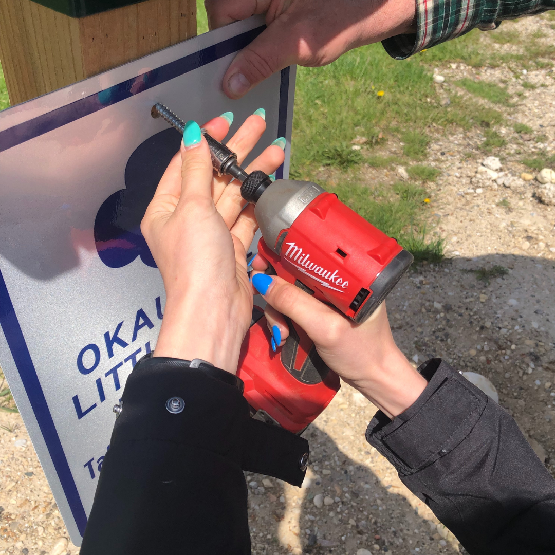 gold award girl scout installing sign on little free pantry