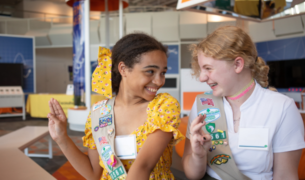 two girl scouts holding girl scout sign and laughing