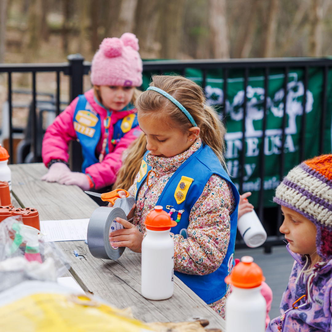 girl scout daisy working on project with tape roll