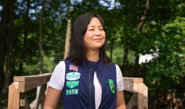 adult woman girl scout volunteer wearing vest outdoors smiling hiking