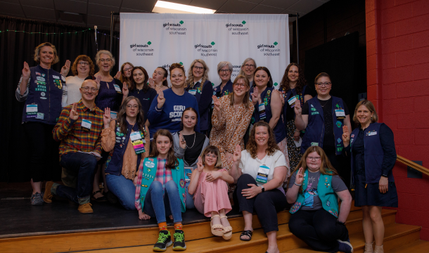 big group of girl scout volunteers posed on stage