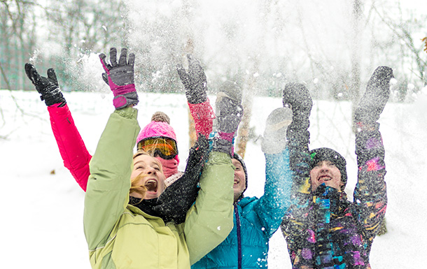 Group of older Girl Scouts throwing snow in the air