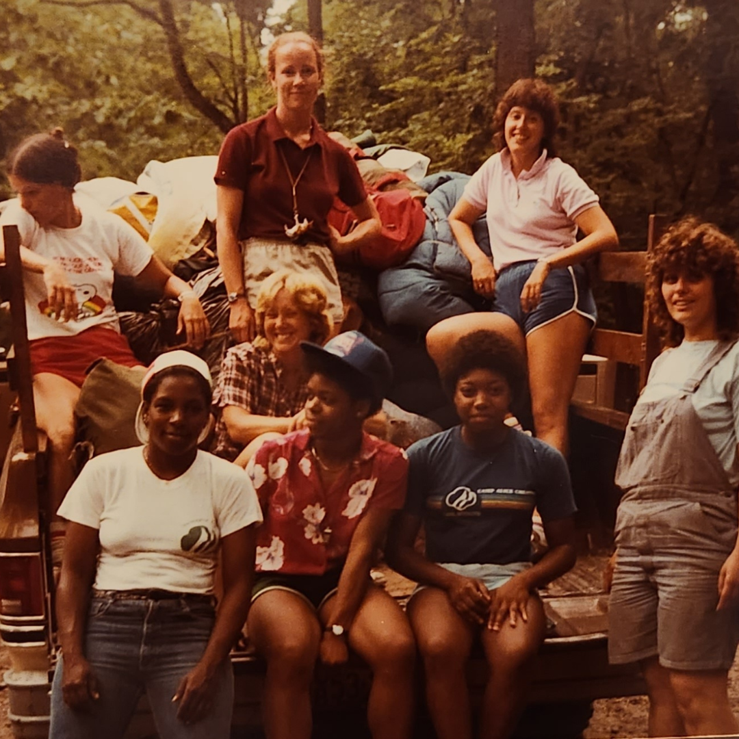 girl scout camp counselors on back of truck smiling at camera