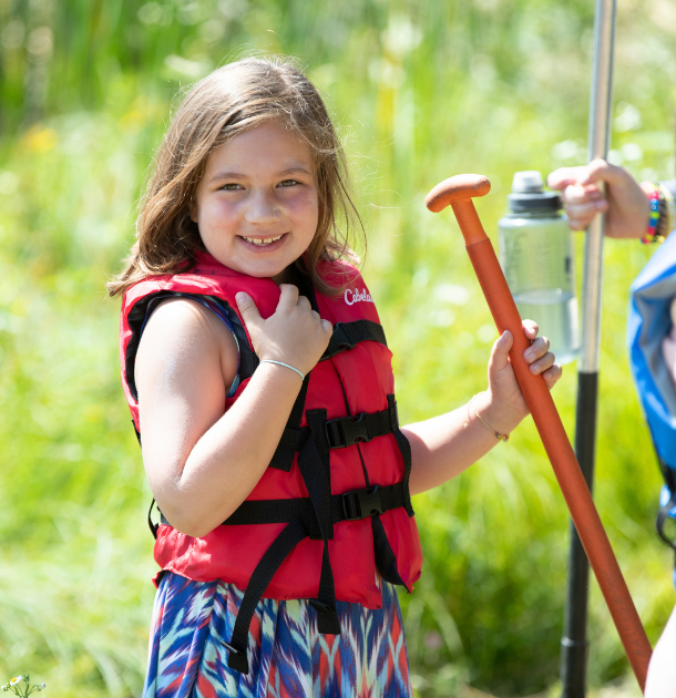 girl scout in life jacket holding canoe paddle