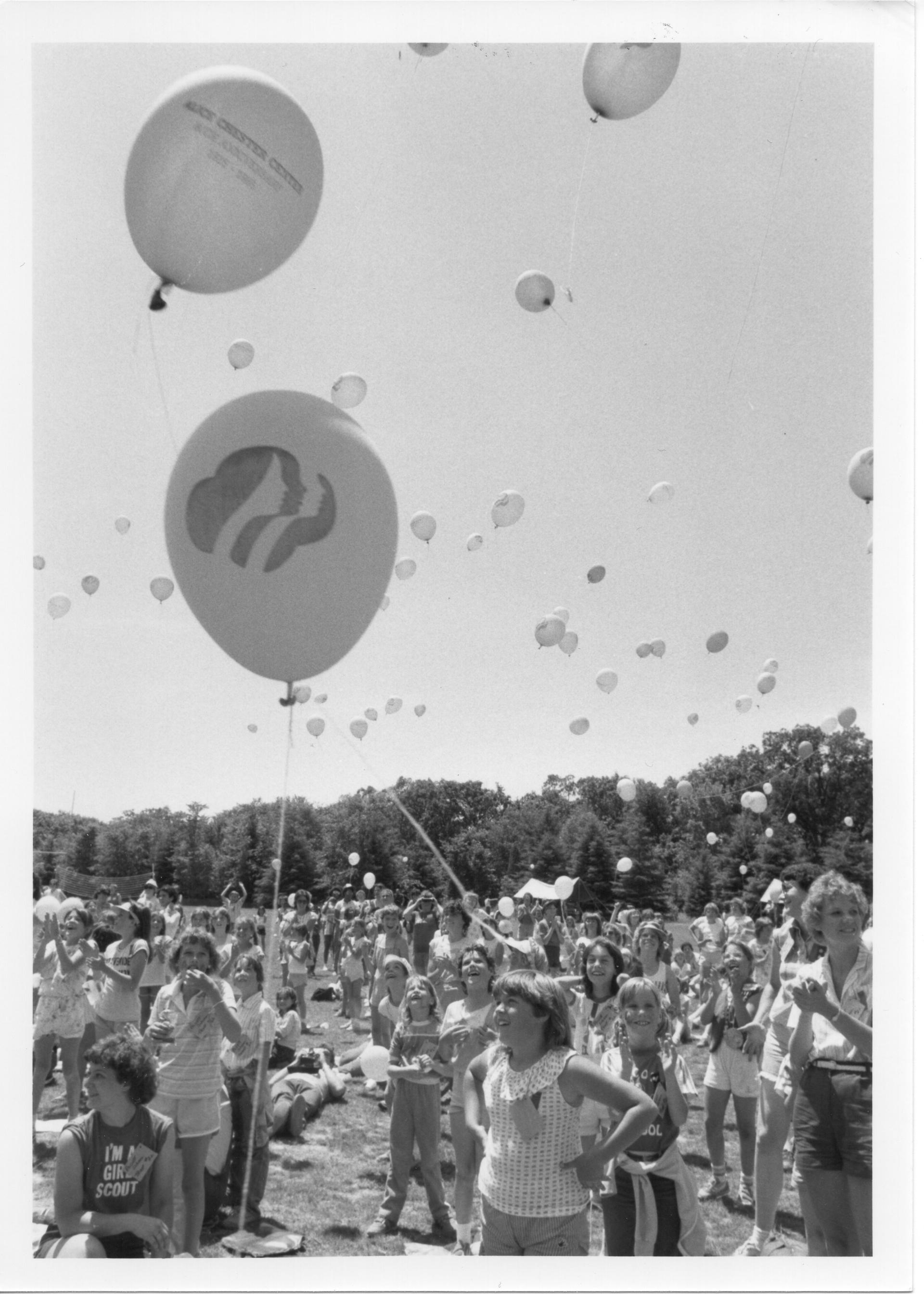 vintage black and white photo of girl scouts with balloon release celebration on sports field
