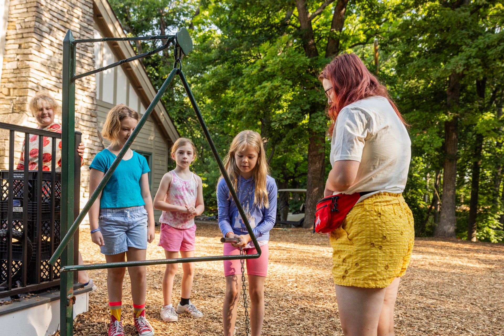 camp counselor and campers ringing meal triangle outdoors