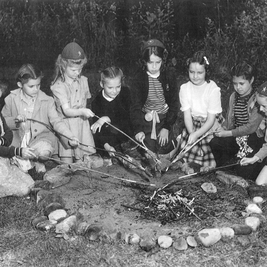 vintage black and white photo of campers roasting marshmallows over fire