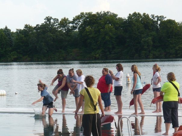 A group of people stand on the pier at Camp Alice Chester's Booth Lake. Andrea Yanacheck is being pushed off of the pier to the delight of her coworkers.