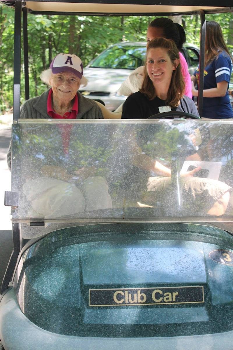 Two women sit in a golf cart at Camp Alice Chester. On the left is Marion Chester Read and on the right is Andrea Yanacheck.