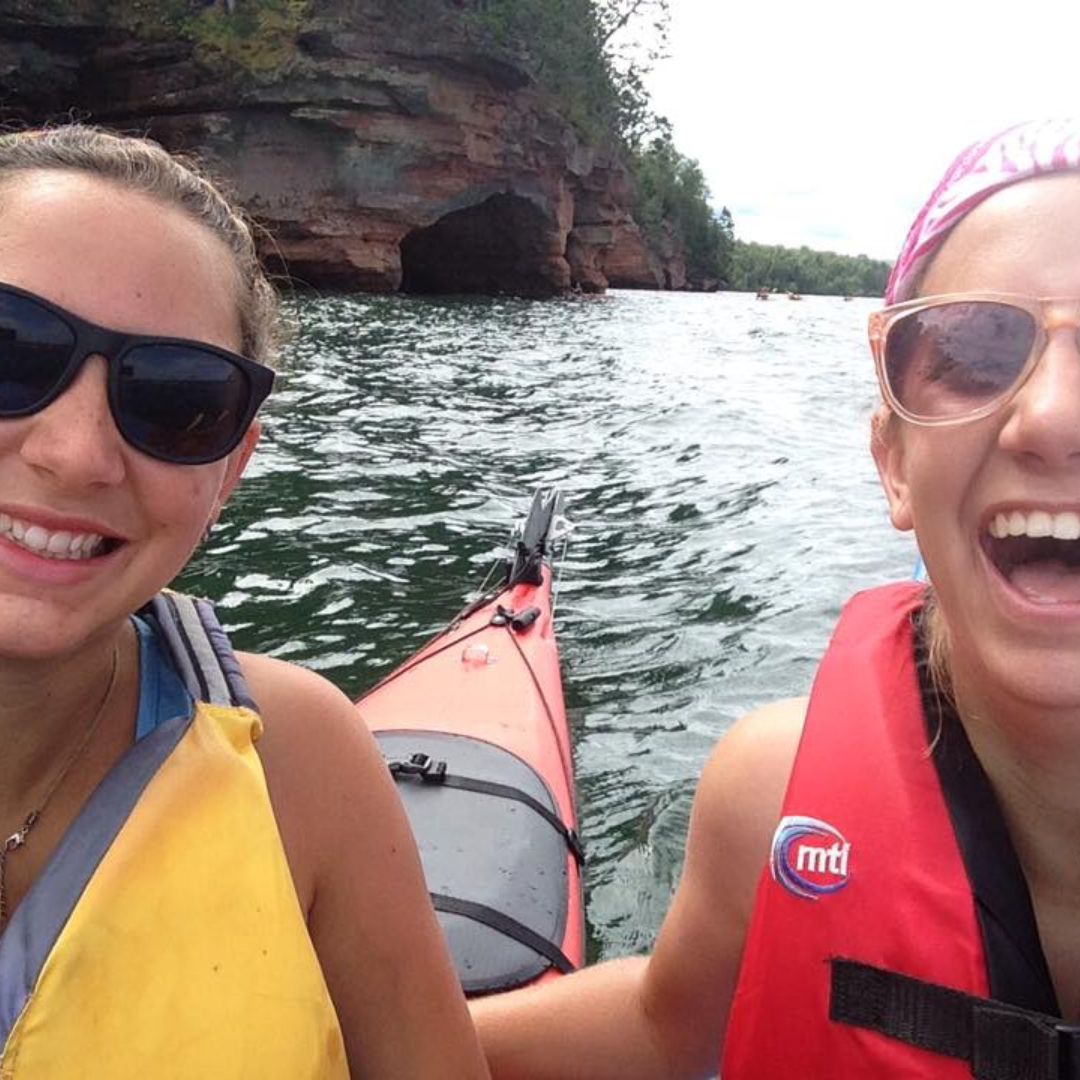 two girls smiling on kayaks in lake