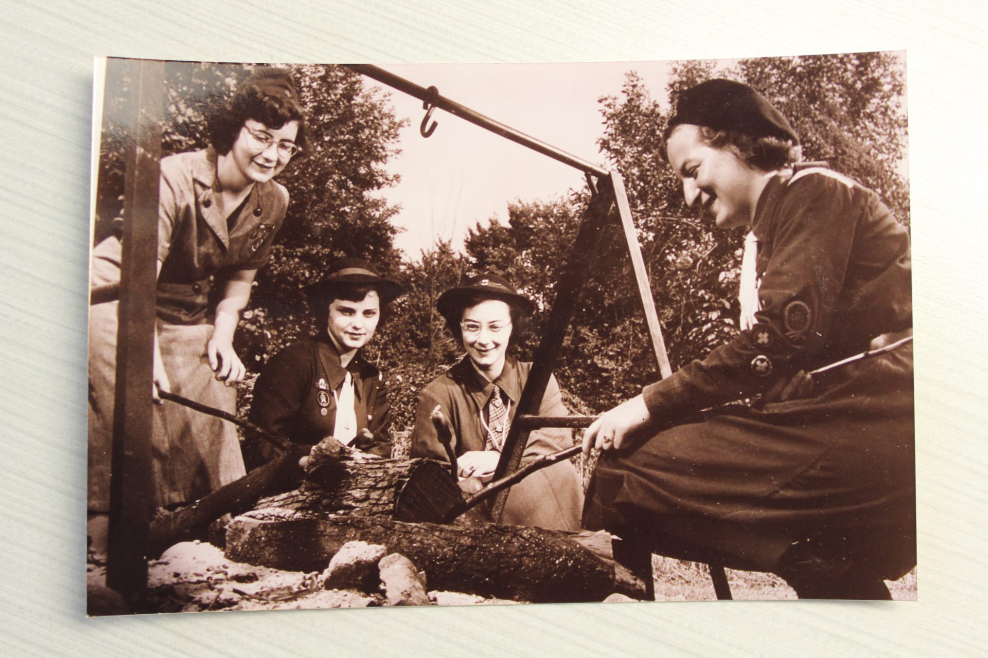 historic vintage sepia photo of girl scouts building fire at camp