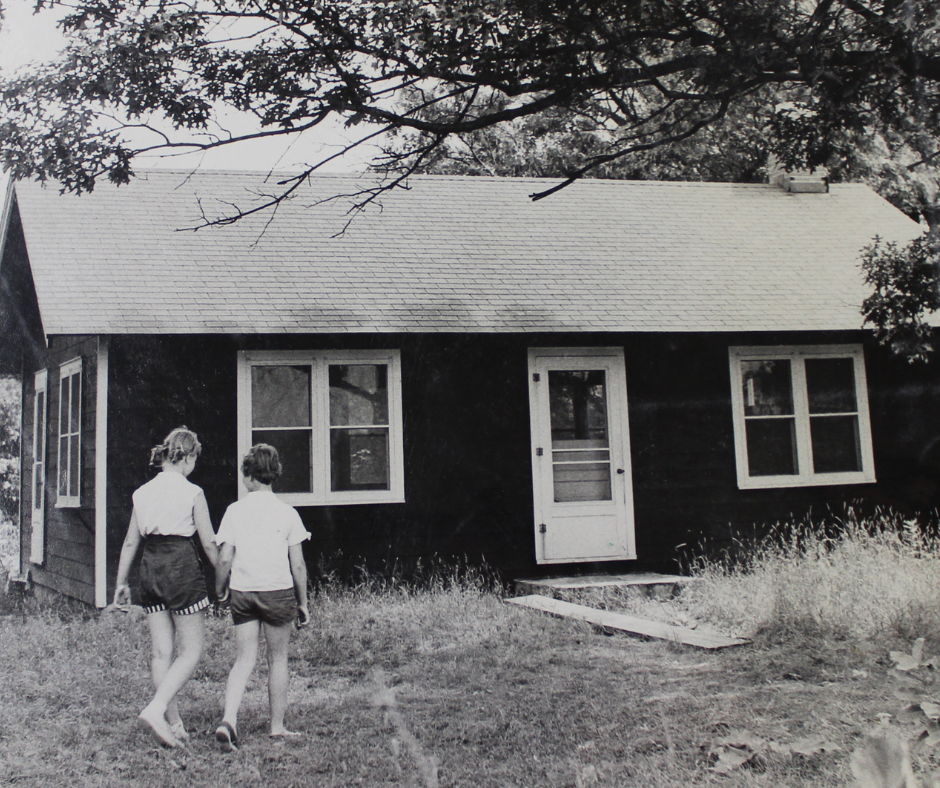 vintage black and white photo of two campers outside of building