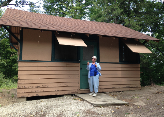 girl scout alum in front of camp lodging