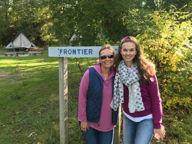camp staff alum and mom posing in front of unit sign