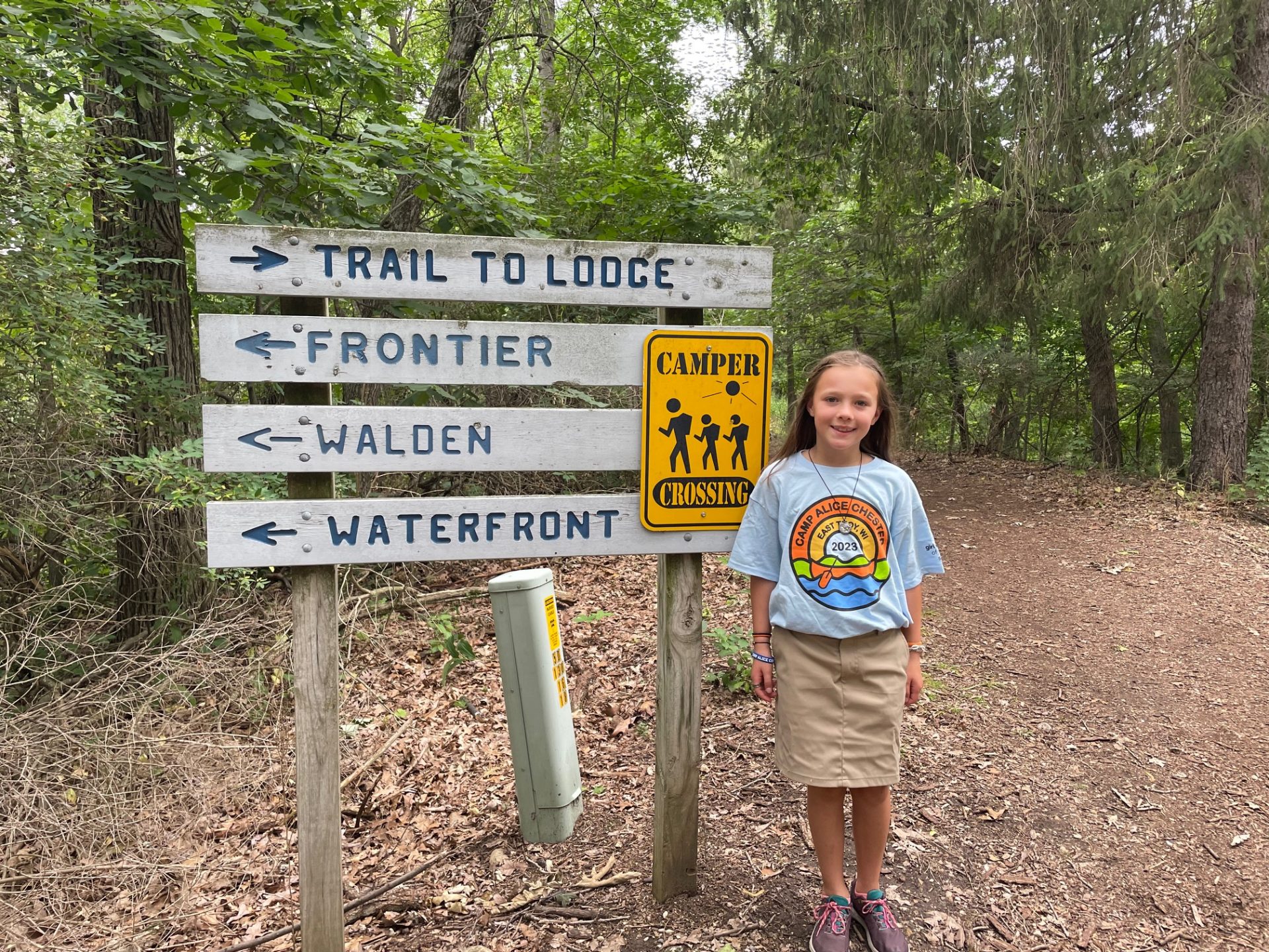 girl scout camper posing in front of unit signs outdoors