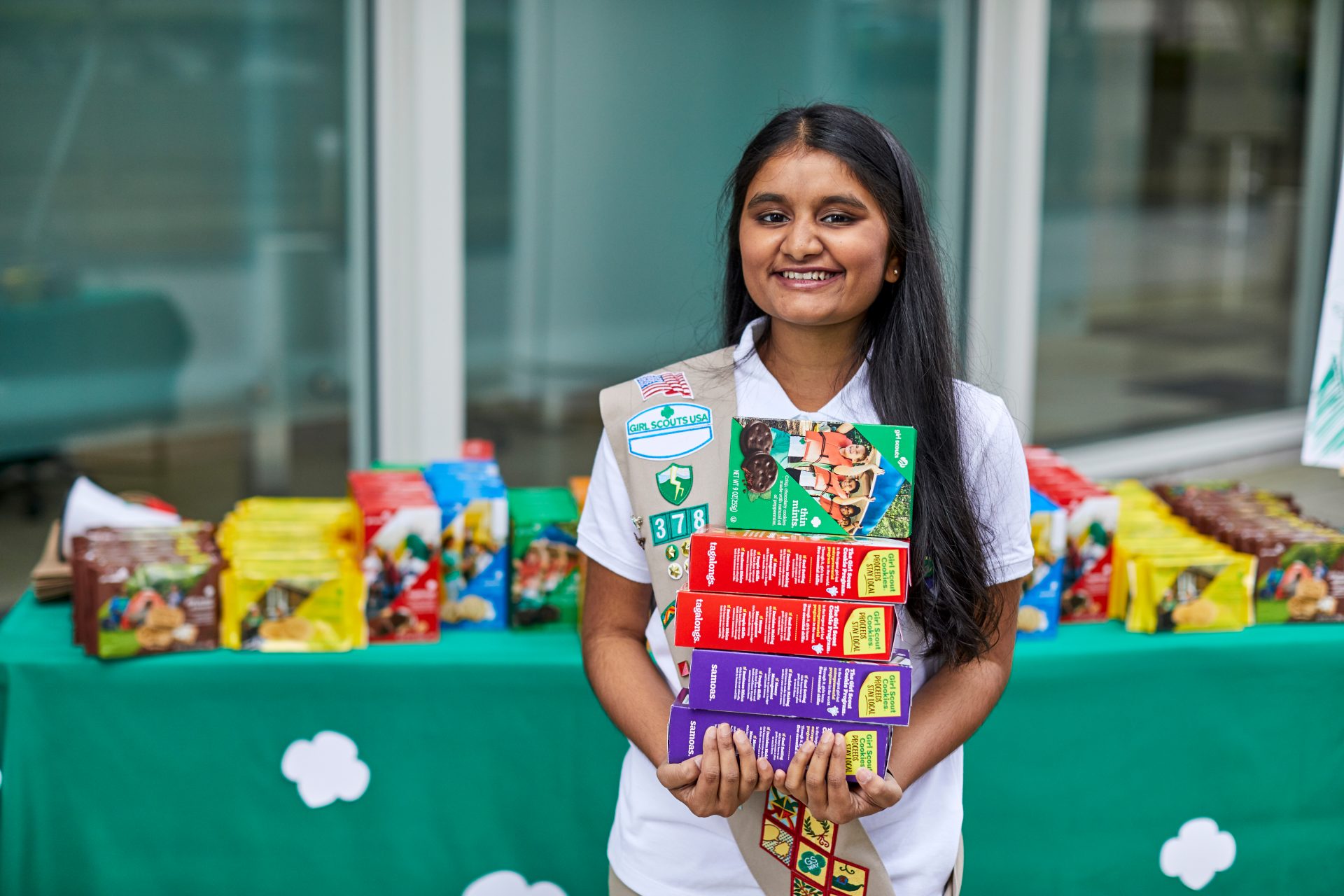 Girl Scout holding stacked boxes of Girl Scout cookies