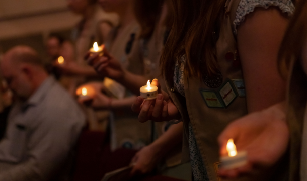 girl scouts holding candles in dim room 