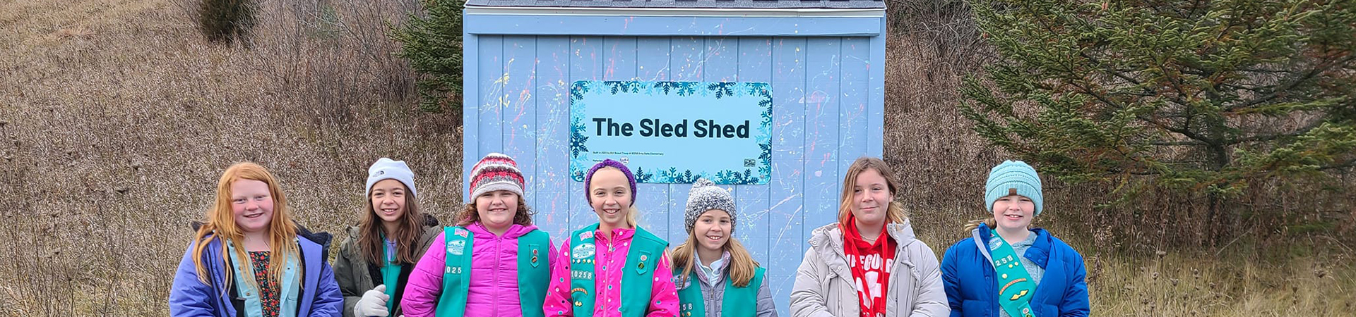 Group of Girl Scouts posing for photo in front of their sled project for their Bronze Award 