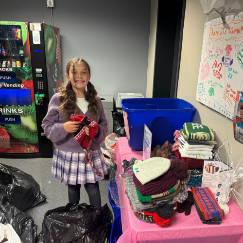 girl scout hosting clothing drive holding up sweaters