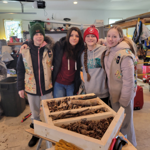 four girl scouts smiling in front of woodworking project
