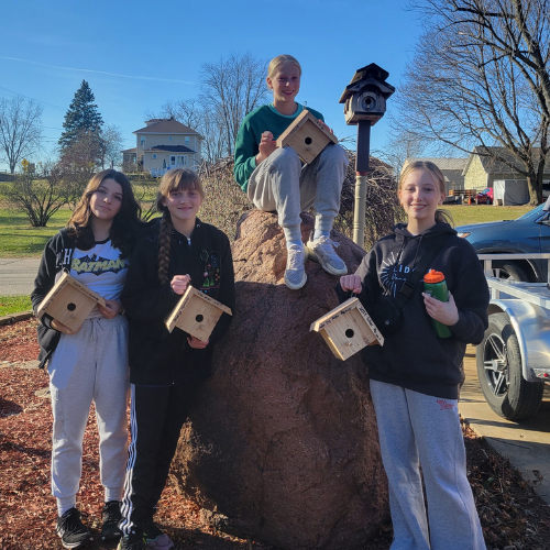 group of girl scouts holding up wood bird boxes