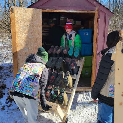 two girl scouts loading shoe rack into shed