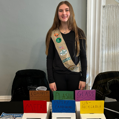 girl scout in front of recycling display