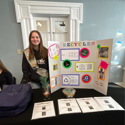 girl scout standing in front of posterboard presentation about recycling