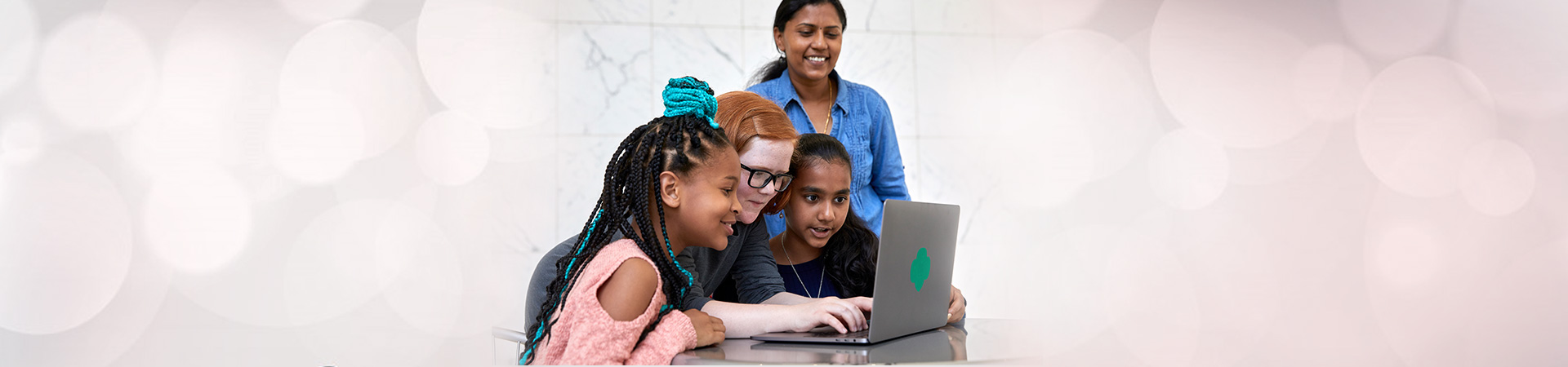  three Girl Scouts and adult looking at laptop 