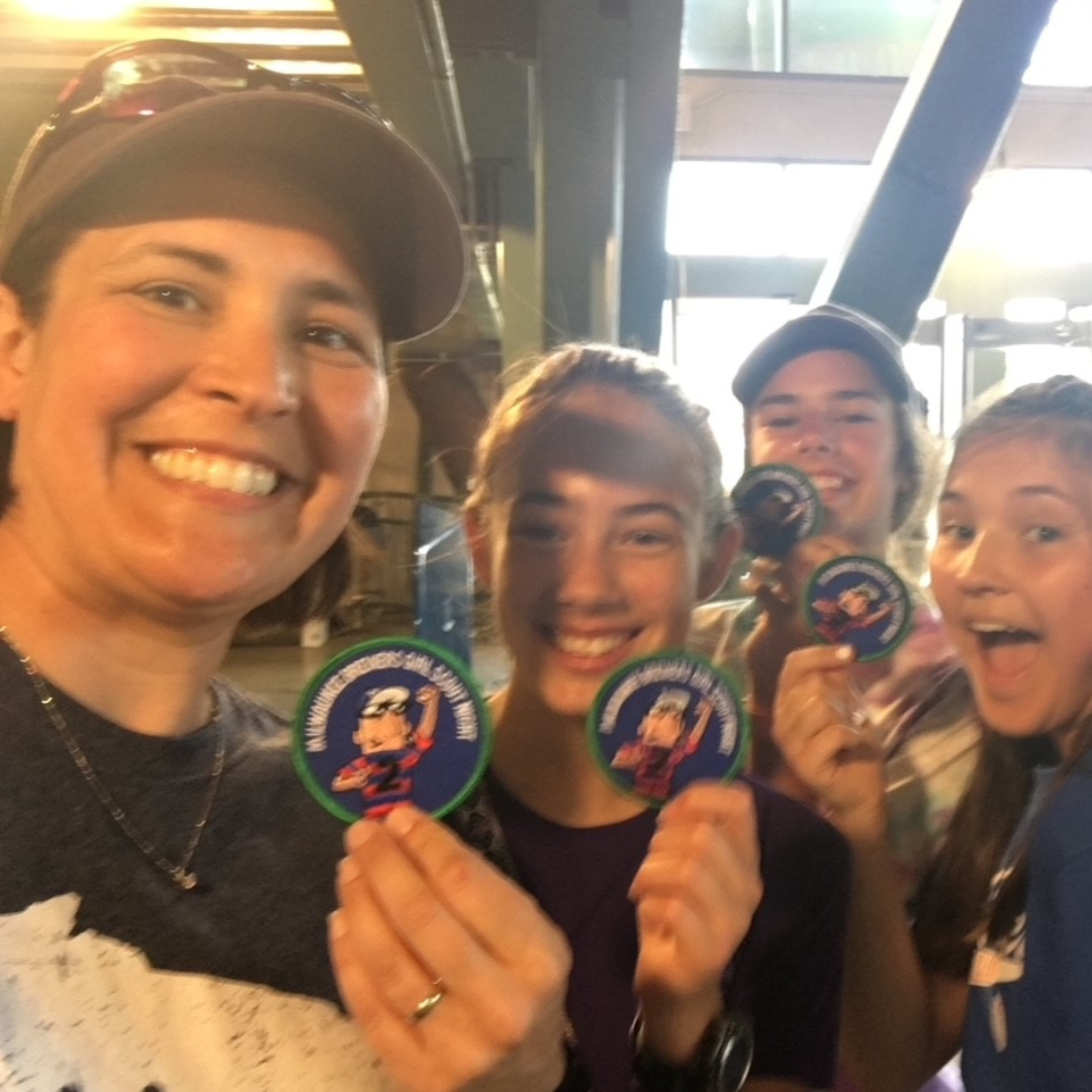girl scout troop leader and troop showing patches in selfie