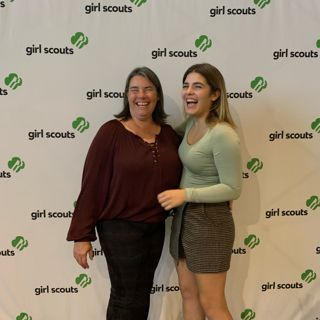 girl scout volunteer and daughter laughing in front of girl scout sign