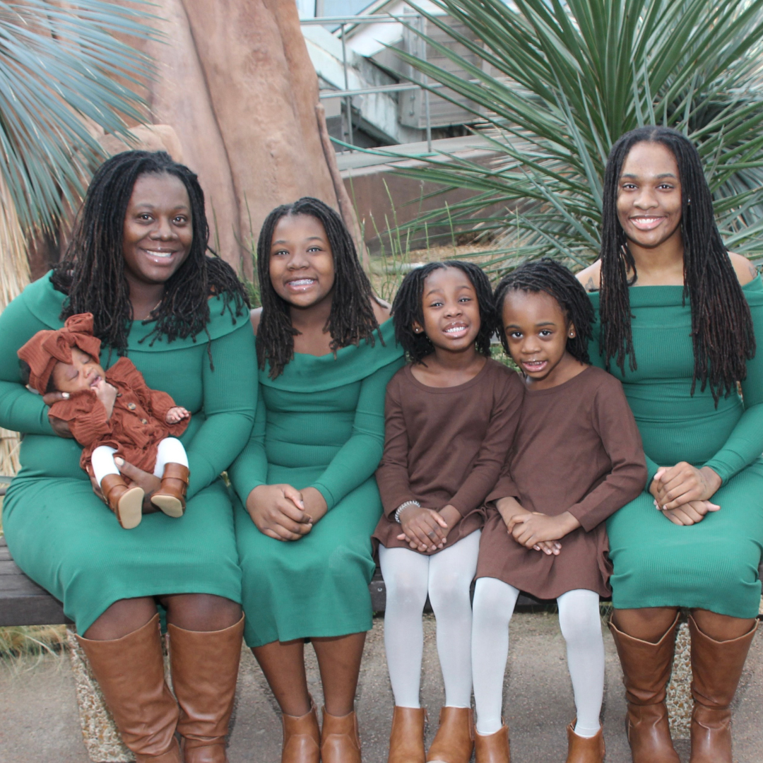 mom and daughters wearing green and brown smiling at camera