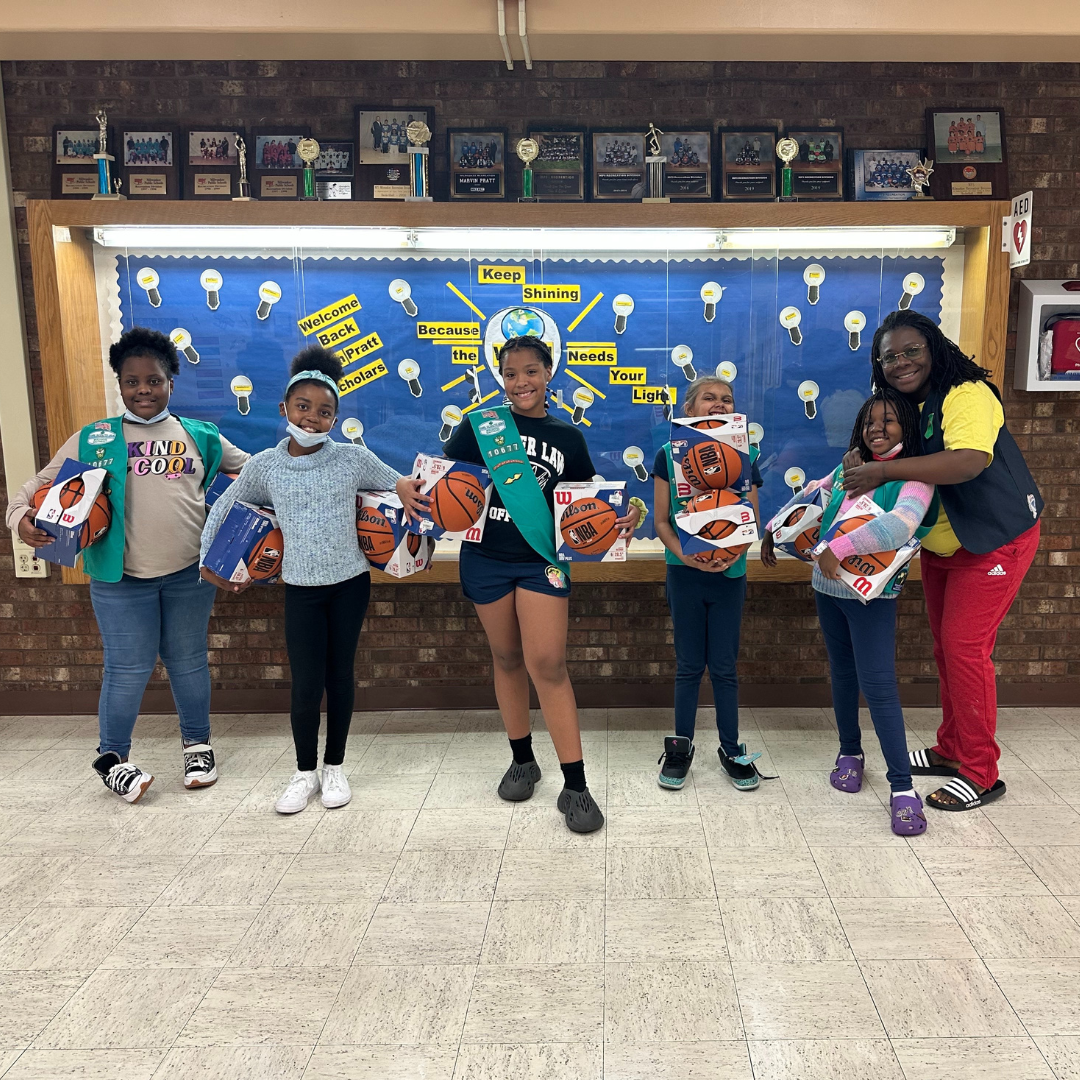 junior girl scouts posing with basketballs and troop leader