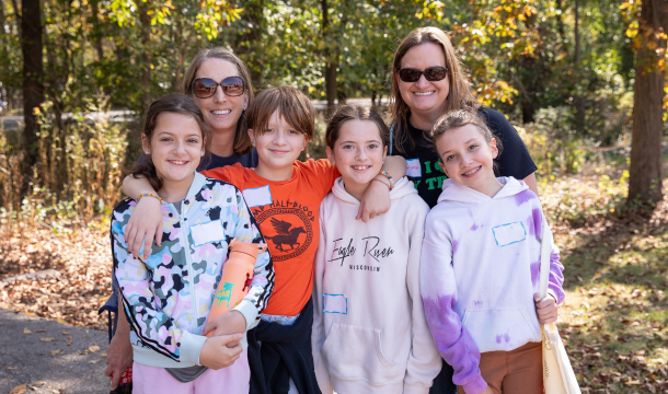two troop leaders smiling behind group of three girl scouts in outdoor setting